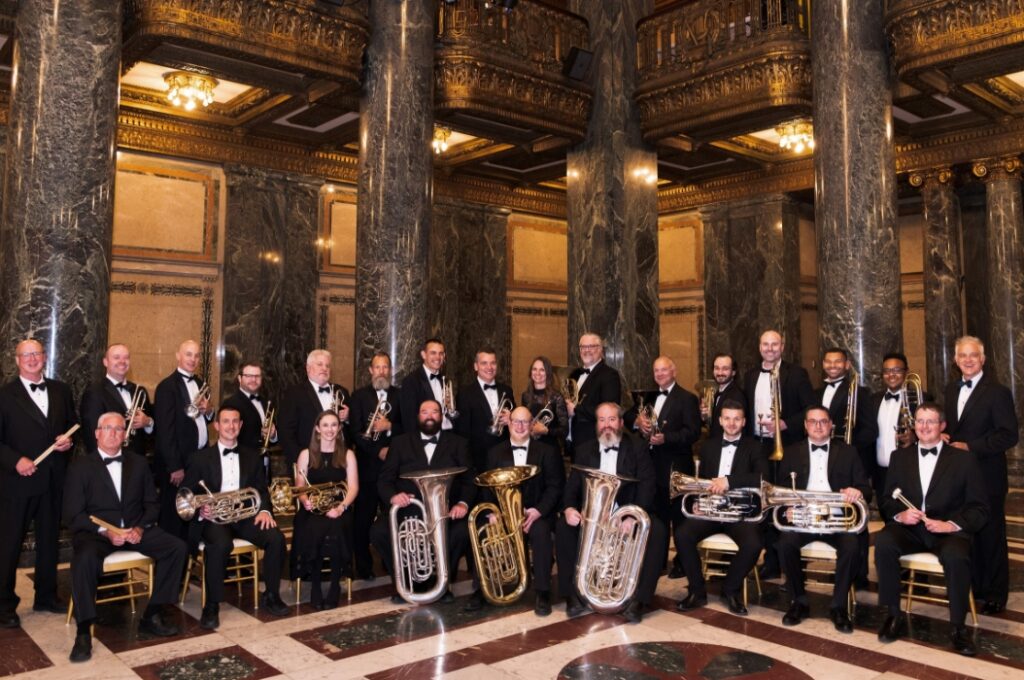 28 Musicians and Conductor in grand hall holding instruments