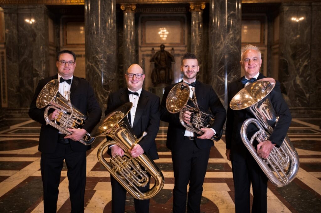 4 musicians in grand hall holding tubas and euphoniums