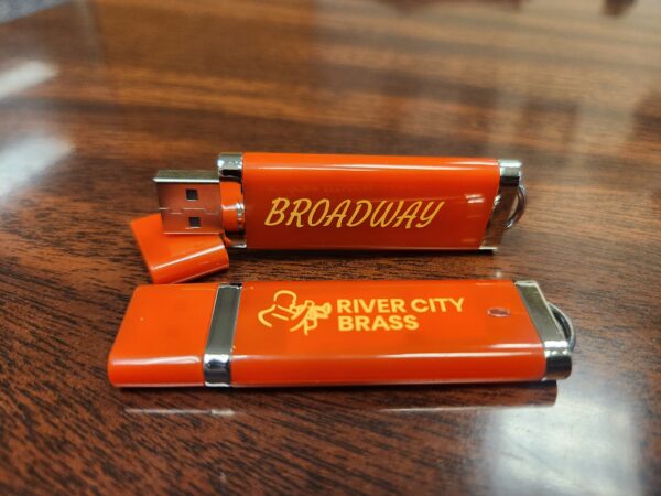 Red thumb drive with gold "Broadway" text and gold River City Brass logo