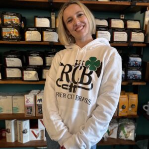 Woman wearing white hoodie with black RCB logo adorned with a green shamrock