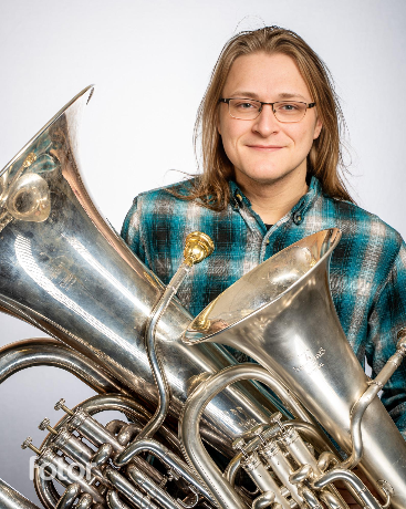 Kasey Higginbotham, man with two tubas in plaid shirt smiling