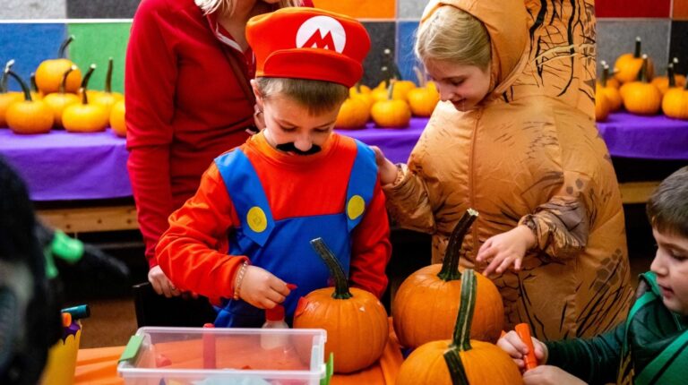 Children in Halloween costumes decorating pumpkins during a Halloween activity